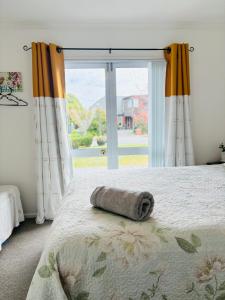 uma toalha enrolada numa cama em frente a uma janela em Home away from home em Christchurch