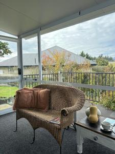uma cadeira de vime sentada num alpendre com uma mesa em Home away from home em Christchurch