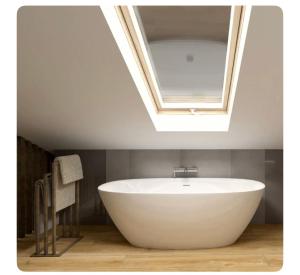 a white bath tub in a bathroom with a skylight at Giles Apart in Edinburgh