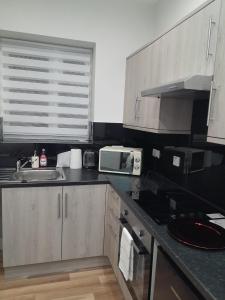 a kitchen with a sink and a microwave at JJ Serviced Apartment - Close to Tube Station & Near Central London & Wembley in Northolt