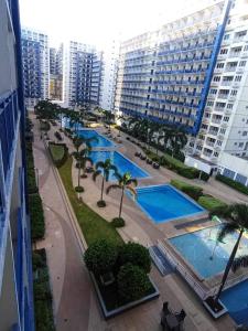 een uitzicht over een zwembad met palmbomen en gebouwen bij Sea Fearer's condotel Pasay Moa in Manilla