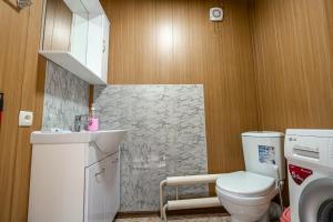 a bathroom with a toilet and a sink and a washing machine at Half,Гостевой дом in Karakol