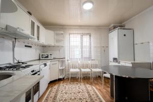 una cocina con electrodomésticos blancos y una mesa con sillas. en Half,Гостевой дом, en Karakol