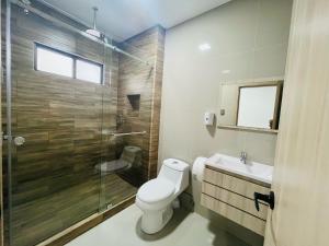a bathroom with a toilet and a glass shower at Vista Hills Loft & Jacuzzi a 10min Consulado Americano in Guayaquil +6 photos