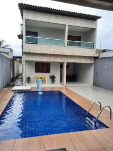 a villa with a swimming pool in front of a house at Casa Buzios do Francês in Marechal Deodoro