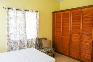 ein Schlafzimmer mit einem Bett, einem Stuhl und einem Fenster in der Unterkunft Hidden Gem Apartments (No.5) in Castries