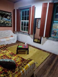 a living room with a bed and a table at Casa Centenária localizada no calçadão de SLP in São Luiz do Paraitinga