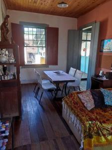 a room with a table and a bed and a bedroom at Casa Centenária localizada no calçadão de SLP in São Luiz do Paraitinga