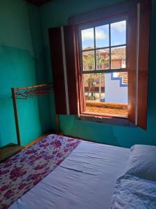 um quarto com uma cama e uma janela em Casa Centenária localizada no calçadão de SLP em São Luiz do Paraitinga