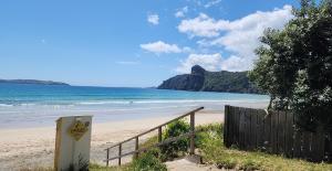 a beach with a wooden fence and the ocean at Kiwiblue in Kerikeri