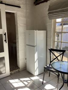 a kitchen with a refrigerator and a table and a chair at Rosewood Cottage Apartment in Himeville