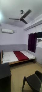 a bedroom with a bed with a ceiling fan and a chair at SPOT ON Gajadhar Rest House in Deoghar