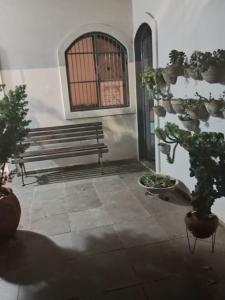 a bench sitting next to a building with potted plants at Pousada Cantinho da Idna - 2 Quartos Disponíveis - 1 solteiro e 1 casal in Uberlândia