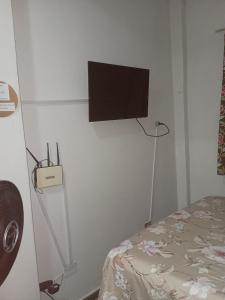 a bedroom with a tv on the wall and a bed at Pousada Cantinho da Idna - 2 Quartos Disponíveis - 1 solteiro e 1 casal in Uberlândia