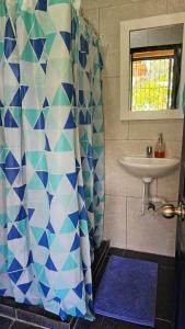y baño con cortina de ducha y lavamanos. en Entre Cantos - Hospedaje Rural en Ibagué