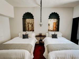 two beds in a room with white walls at CASA REGINA Hotel - Cantina SMA in San Miguel de Allende