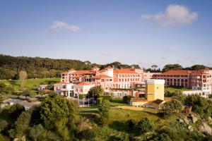 un groupe de bâtiments sur une colline plantée d'arbres dans l'établissement Penha Longa Resort, à Sintra