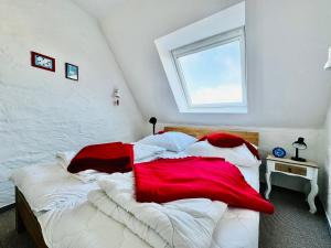a bedroom with a large bed with red and white blankets at Godewind Ausguck C3 in Kronsgaard