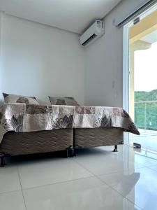 Bett in einem weißen Zimmer mit einem großen Fenster in der Unterkunft Estadia Wolf Lencois in Lençóis