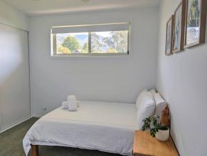 una camera bianca con un letto e una finestra di Gumleaf Retreat a Mount Beauty