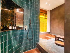 baño con ducha de azulejos verdes en 云缦·兮温泉民宿, en Xinzhou