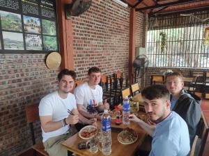 Eine Gruppe Männer, die an einem Tisch in einem Restaurant sitzen in der Unterkunft Nhà Điệp Bungalow Ninh Binh in Ninh Bình