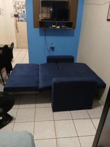 um sofá azul num quarto com uma televisão em Kitinete perto da praia e Shopping Brisamar em São Vicente, na Biquinha, temporada e mensal tudo incluso, mobiliado, wi fi, ventilador, elevador, horário flexível em São Vicente