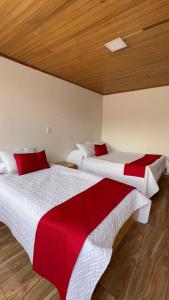 two beds in a room with red and white sheets at HOTEL SUAREL CENTER in Duitama
