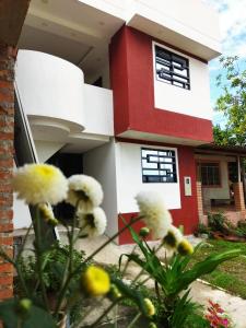 San Vicente de Chucurí的住宿－KOKOA GARDEN INN，一座红白色房子,前面有鲜花