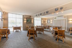 un comedor con mesas, sillas y ventanas en Posthouse Motor Lodge, en Goulburn