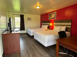 Cette chambre comprend deux lits et un bureau. dans l'établissement Thruway Holiday Motel, à Westfield