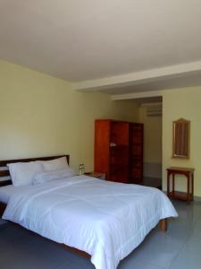 um quarto com uma grande cama branca e um armário de madeira em Pesona Room and restaurant em Labuan Bajo