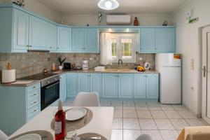 a kitchen with blue cabinets and a white refrigerator at Militsa House in Gaios +11 photos