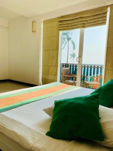 a bedroom with a large bed with a view of the ocean at Saprin Beach By Travel Corners in Uswetakeiyawa