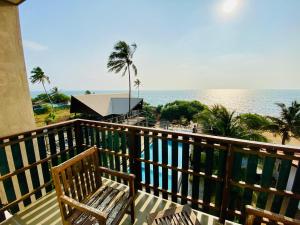 a wooden balcony with a bench and the ocean at Saprin Beach By Travel Corners in Uswetakeiyawa
