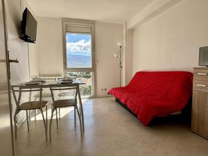 um quarto com uma cama vermelha, uma mesa e uma janela em Appartement Argelès-sur-Mer, 2 pièces, 4 personnes - FR-1-225-814 em Argelès-sur-Mer