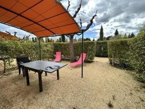 un tavolo e sedie sotto un ombrellone arancione di Maison L'Isle-sur-la-Sorgue, 3 pièces, 4 personnes - FR-1-767-20 a LʼIsle-sur-la-Sorgue