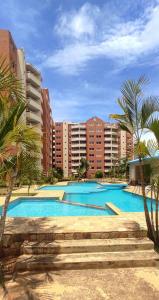a large swimming pool with palm trees and buildings at Ubicación Ideal - Playa El Ángel, Pampatar in Pampatar