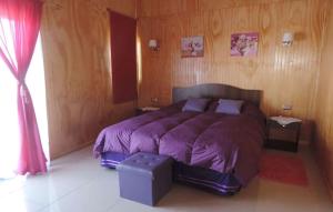1 dormitorio con 1 cama grande con sábanas moradas en Cabañas el mirador de Rio Claro en Río Claro