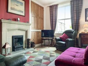 a living room with a fireplace and a purple couch at Rock Terrace View in Bakewell