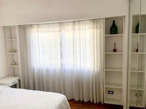 1 dormitorio con cama y cortina blanca en Teodoro's Home en Buenos Aires