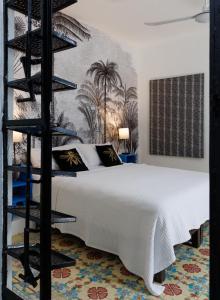 a bedroom with a white bed and a black shelf at PLENO CENTRO MERIDA ESTUDIO3 CASA PAXI in Mérida