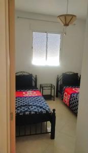 1 Schlafzimmer mit 2 Betten und einem Fenster in der Unterkunft Appartement almontazah aljadid à côté de Marjane Marrakech in Marrakesch