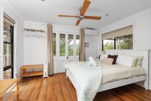 a white bedroom with a bed and a ceiling fan at Wild Rose Cottage Kiaroo Estate, Kangaroo Valley in Kangaroo Valley
