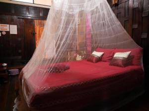 uma cama vermelha com uma rede por cima em Baan Are Gong Riverside Homestay em Phra Nakhon Si Ayutthaya