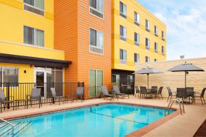 a pool with chairs and umbrellas next to a building at Fairfield Inn & Suites by Marriott El Paso Airport in El Paso
