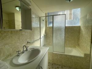 a bathroom with a sink and a tub and a mirror at Wyuna - Walking distance to burleigh in Gold Coast