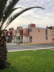un edificio con una palmera frente a una calle en Cómoda Casa 3Hab: Piscina, Seguridad, Parking en Emiliano Zapata