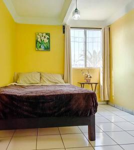 Dormitorio amarillo con cama y ventana en Cómoda Casa 3Hab: Piscina, Seguridad, Parking en Emiliano Zapata
