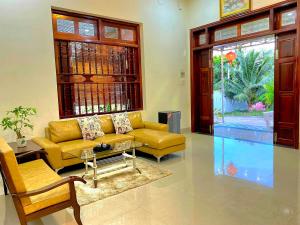 a living room with a yellow couch and a glass table at Peaceful Villa Seaview - From The Beach 400m in Phan Thiet